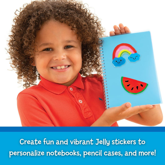 Smiling child holding a blue notebook decorated with colorful jelly stickers of a rainbow and a watermelon slice.