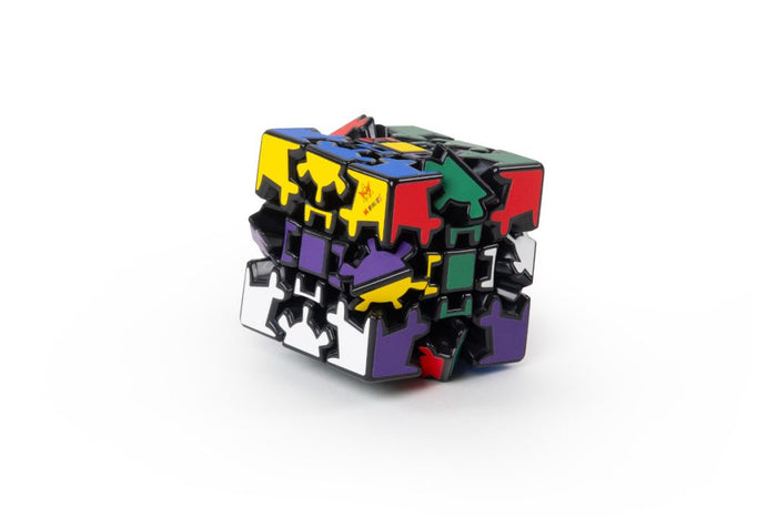 Scrambled black puzzle cube with interlocking gear-shaped pieces and colorful yellow, blue, red, and purple stickers.