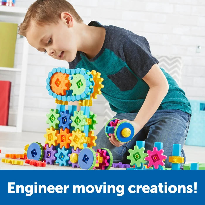 A child building a large structure with colorful interlocking plastic gears and wheels on a carpeted floor.