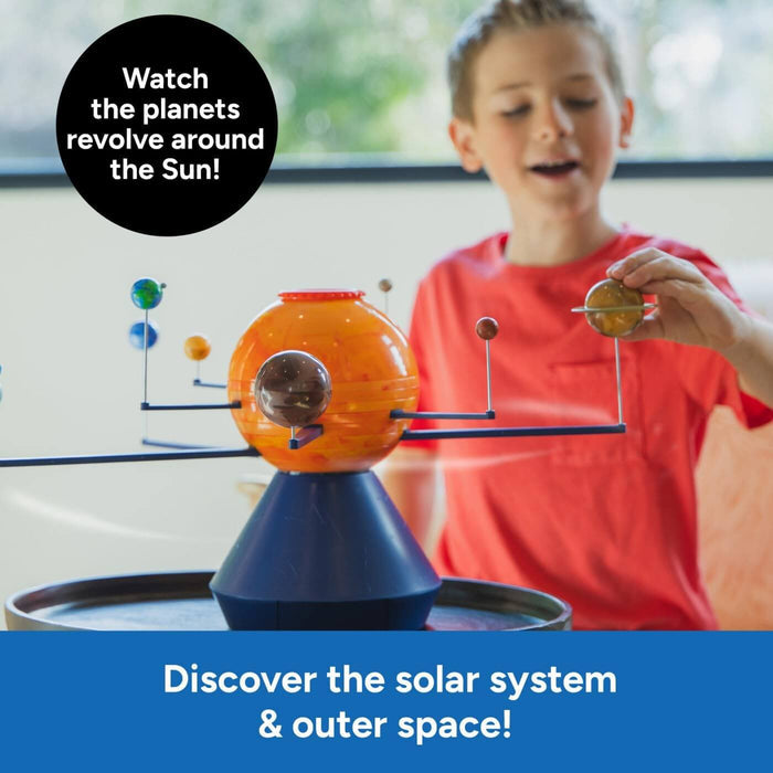 Child plays with a motorized toy solar system featuring a large orange sun and colorful planets on rotating blue arms.