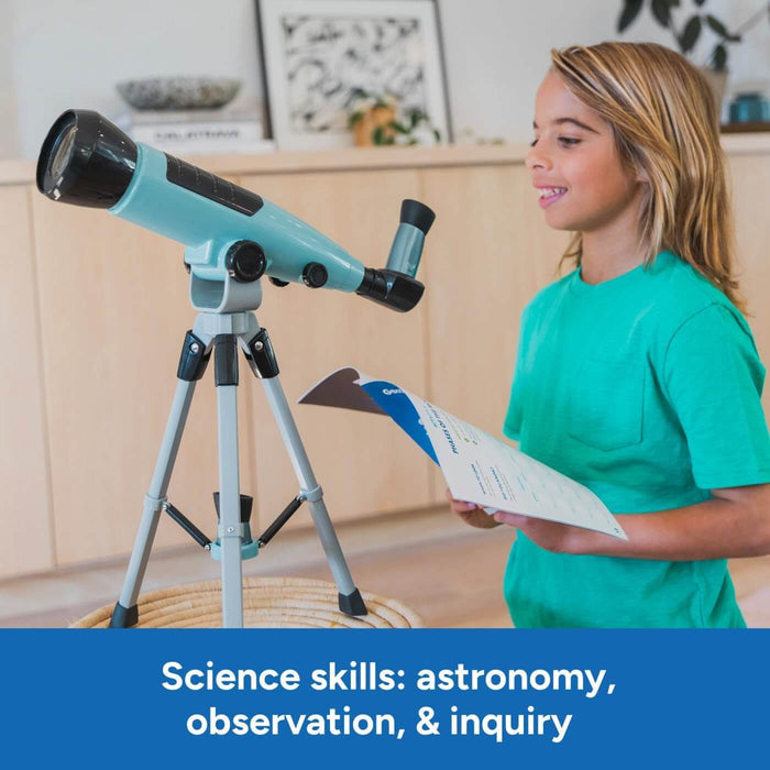 Teal and black telescope on a silver tripod next to a girl in a green shirt holding a science activity guide.