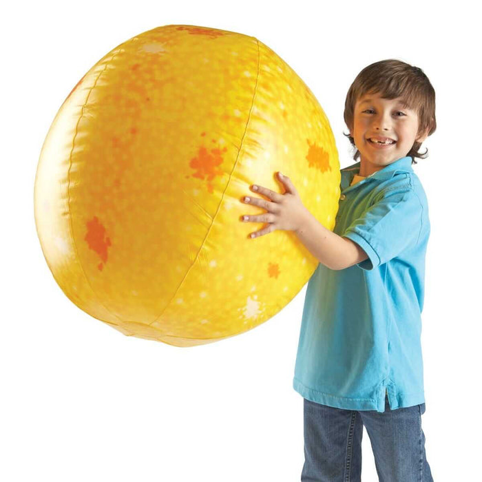 A child holding a large, round yellow inflatable sun with orange sunspot markings.
