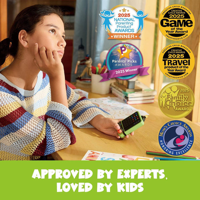 Girl at a desk holds a lime green handheld electronic puzzle game, with several toy award seals in the background.