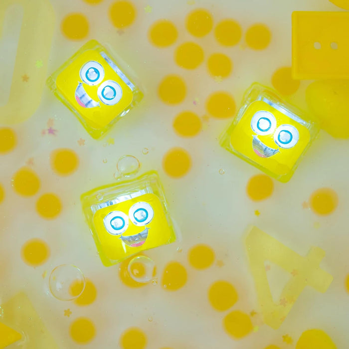 Three yellow cubes with smiling faces floating in a bubbly yellow liquid with translucent yellow shapes and stars.