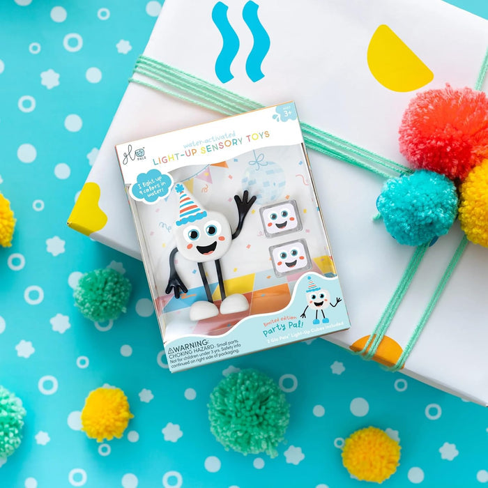 White character with a party hat and two light-up cubes in a decorative box, set against a festive blue background.