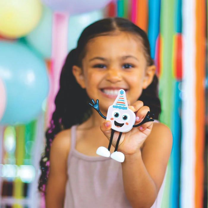 Smiling girl holding a white character toy with a blue striped party hat and black bendy arms and legs.