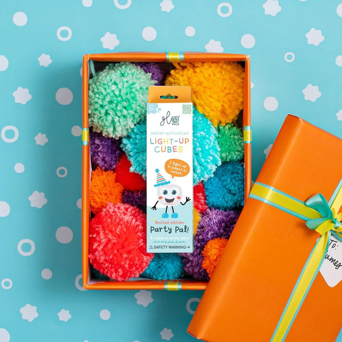 Glo Pals Party Pal box in an orange gift box filled with rainbow pom-poms on a light blue background.