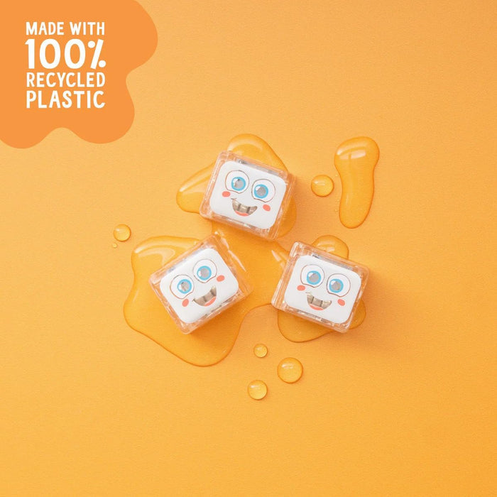 Three clear light-up cubes with smiling faces and blue eyes sitting in pools of liquid on a bright orange background.