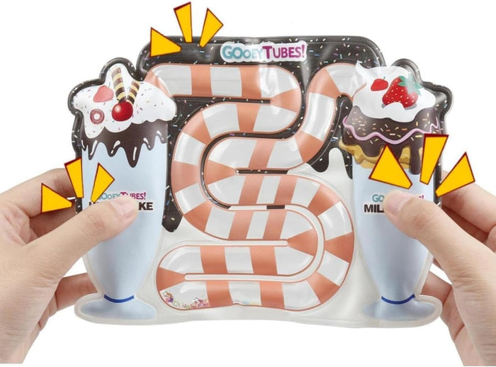 Hands squeezing a milkshake sensory toy with a winding, orange-striped tube filled with liquid and glitter.