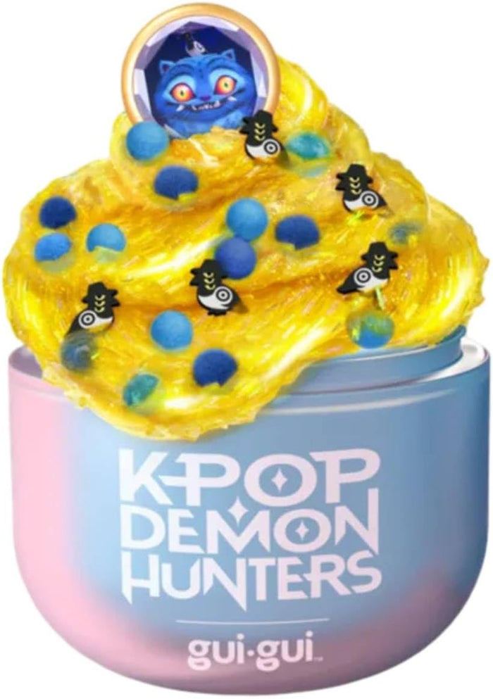Yellow glittery slime with blue beads and character charms in a pink and blue K-Pop Demon Hunters container.