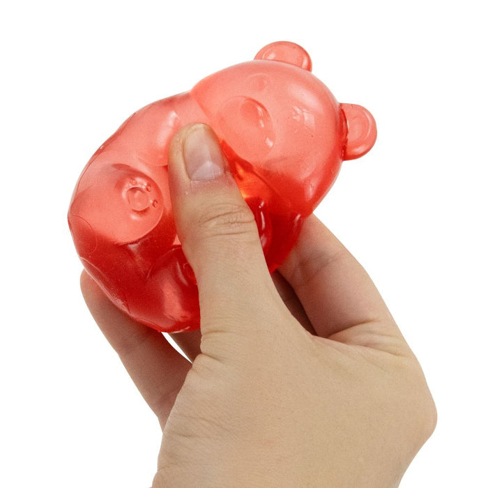 A hand squeezes a red, translucent gummy bear-shaped squishy toy.