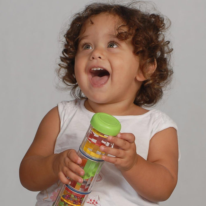 A toddler holds a clear cylinder toy with red, yellow, and green spinning plates and beads, topped with a green cap.