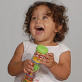 A toddler holds a clear cylinder toy with red, yellow, and green spinning plates and beads, topped with a green cap.