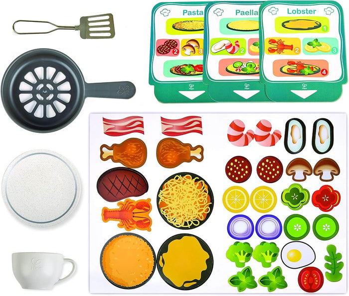 Toy kitchen set with a black fan fryer, spatula, white mug, recipe cards, and various colorful play food cutouts.