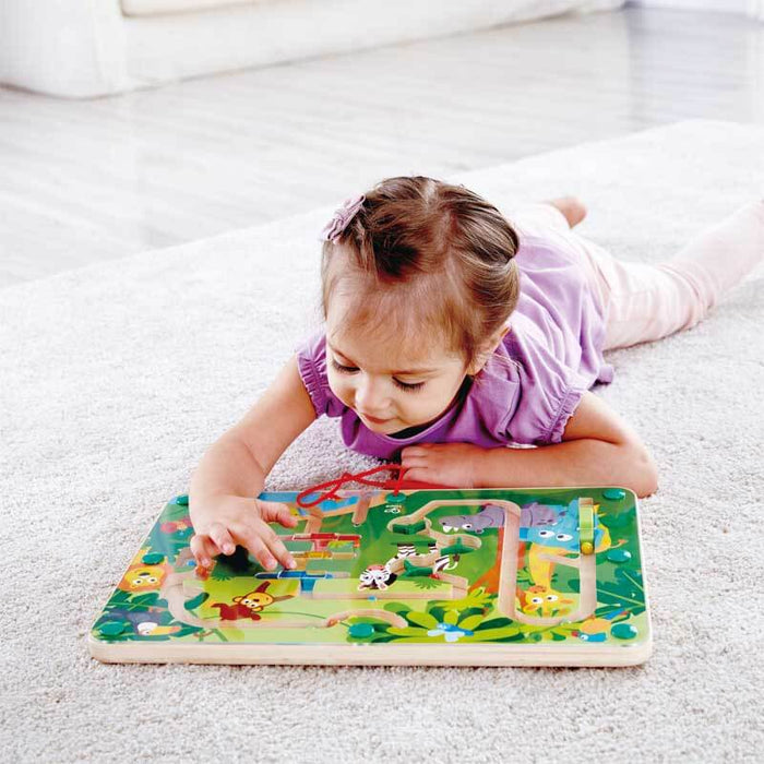 Child on a carpet playing with a wooden magnetic maze toy featuring colorful jungle animal illustrations.