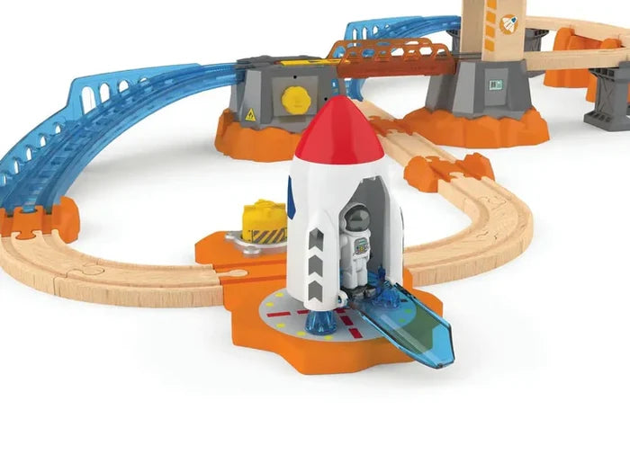 Space-themed toy train set with a white rocket, astronaut, blue plastic tracks, and wooden rails on orange rock bases.