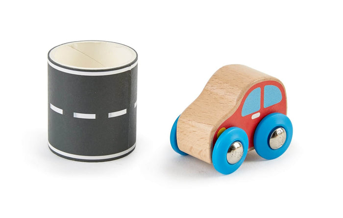 Small wooden toy car with red sides and blue wheels next to a roll of black road tape with white dashed lines.