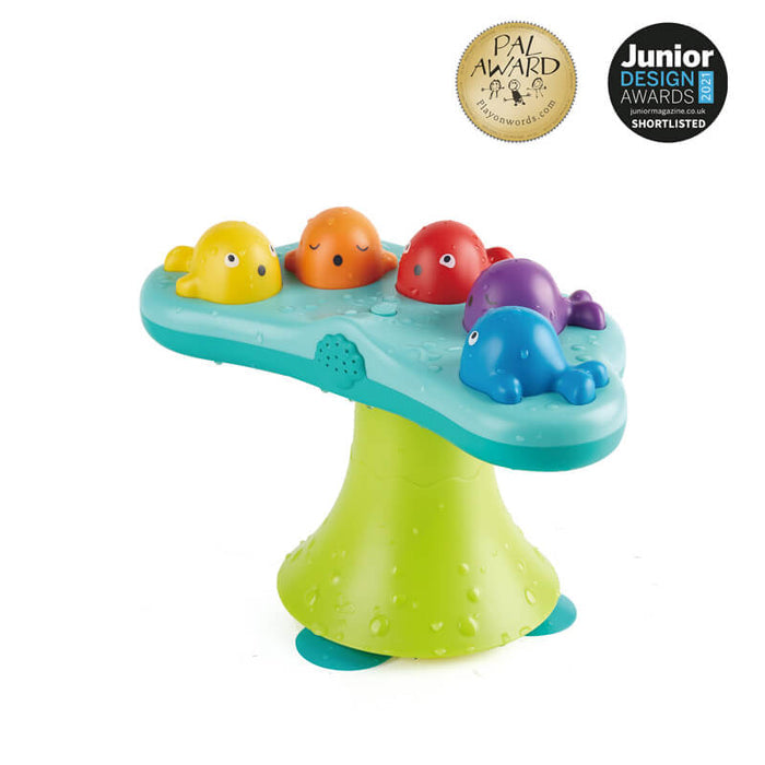 Five colorful plastic whales on a light blue and green fountain base with suction cups and water droplets.