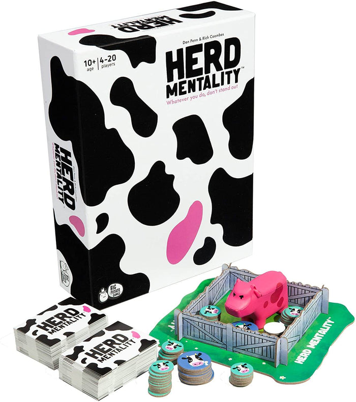Cow-patterned game box with card decks, tokens, and a pink cow figurine inside a cardboard fence on a green base.