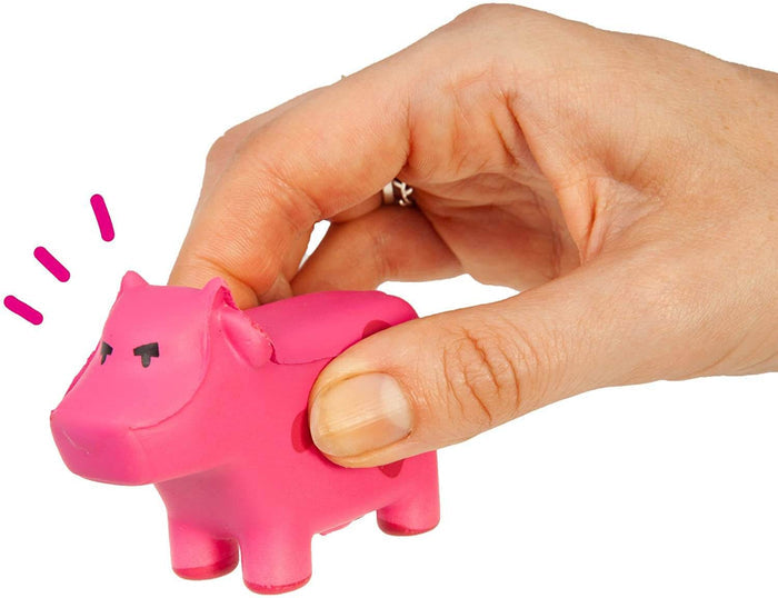 Hand squeezing a small, squishy pink cow toy with simple black eyes and pink motion lines near its head.