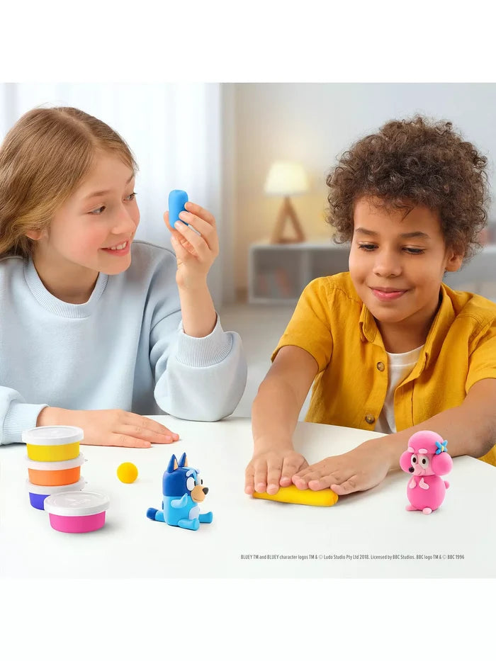 Two kids mold Bluey and Coco characters using vibrant tubs of blue, pink, and yellow clay on a white table.