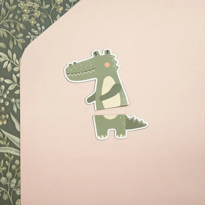 Two-piece green crocodile magnet on a beige rose background with a floral pattern in the corner.