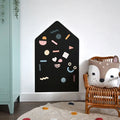 House-shaped black magnetic board on a white wall with colorful magnetic shapes in a child's room.