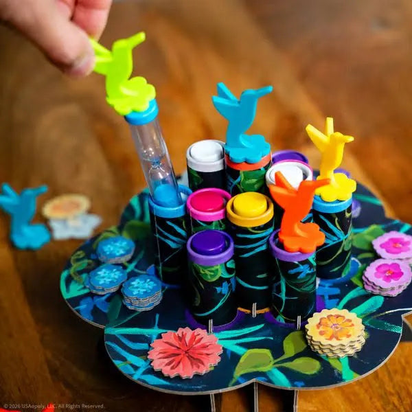 Hand inserting a green bird timer into a tropical board game with colorful bird figurines and floral tokens.