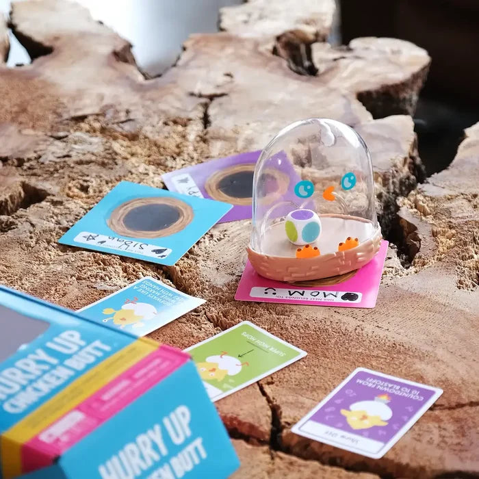 Clear shaker dome with a colorful die and illustrated action cards on a rustic wooden log surface.