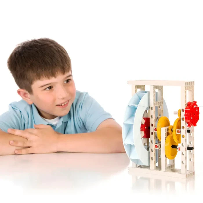 Boy looks at a white STEM toy frame with a light blue water wheel and yellow plastic gears.