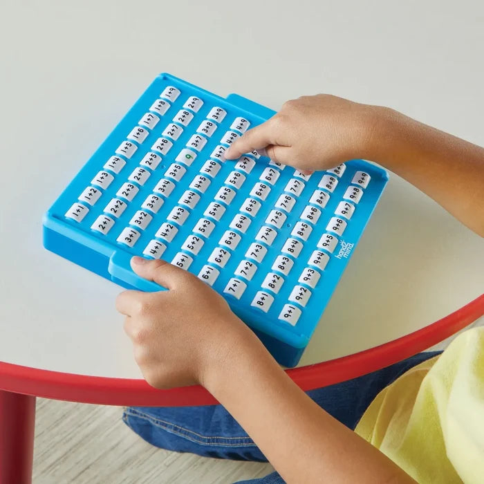 Child's hands press white buttons on a blue plastic board with addition problems like 1+1 and 9+9.