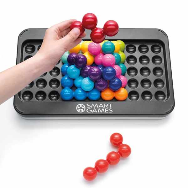 Hand placing a red spherical piece onto a colorful 3D stack on a large grey Smart Games puzzle board.