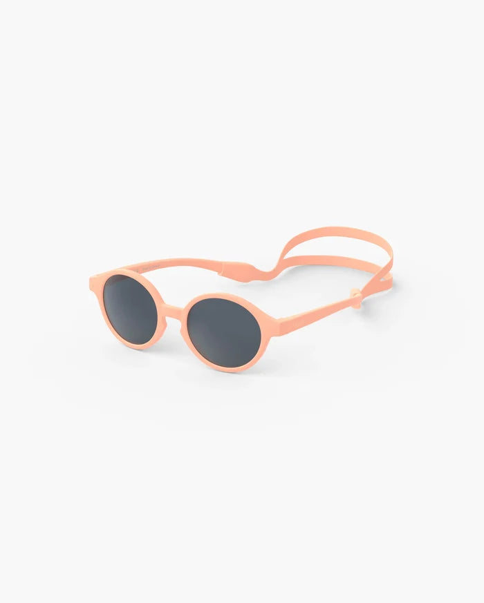 Peach round baby sunglasses with dark lenses and an adjustable silicone head strap.
