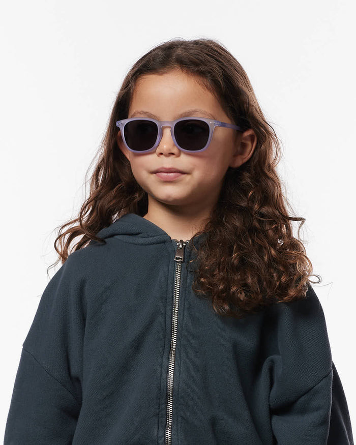 Child wearing light purple square sunglasses with dark lenses and a dark grey zip-up hoodie.