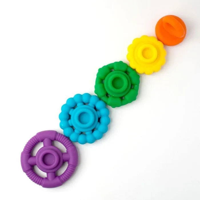 Five textured silicone rings in purple, blue, green, yellow, and orange arranged diagonally on a white background.