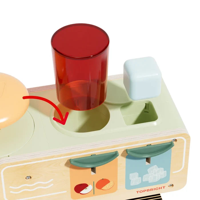 Wooden juice dispenser toy with a red cup and blue ice cube being placed into matching shape-sorting slots.