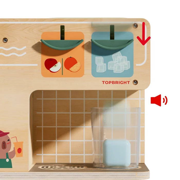 Wooden toy juice machine with fruit icons. A blue ice cube falls into a clear cup next to a red sound effect icon.