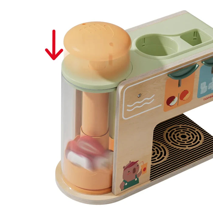 Wooden toy blender with red fruit pieces inside. A red arrow points down to an orange plunger at the top.