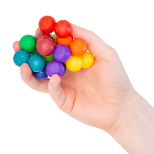 Hand holding a cluster of smooth, brightly colored connected spheres in rainbow shades.