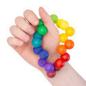 Hand holding a loop of interconnected, vibrant rainbow-colored wooden spheres.