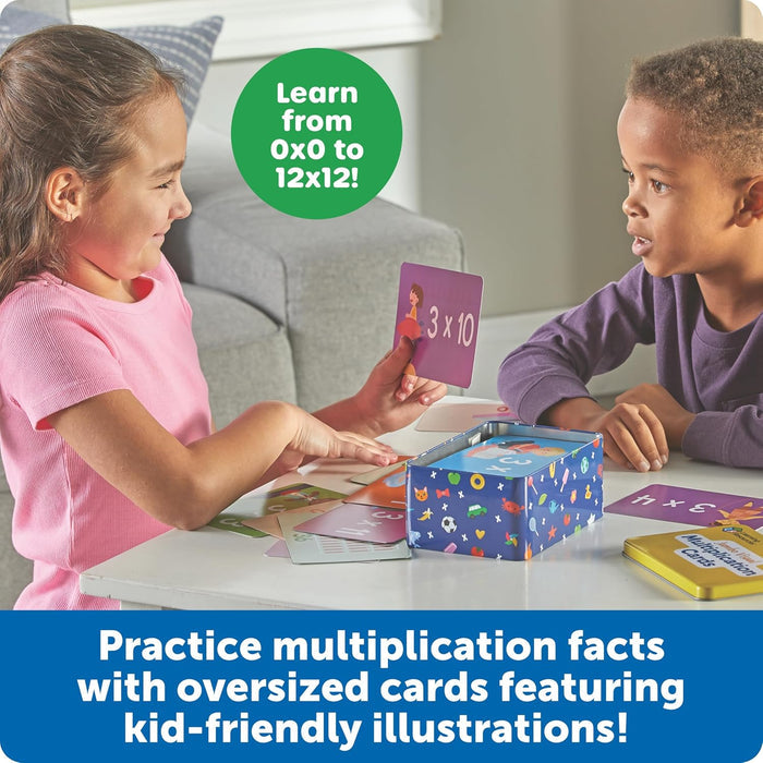 Two kids using oversized math cards with illustrations and a blue patterned storage tin at a white table.