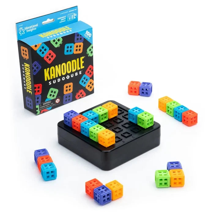 Colorful square puzzle pieces with cutouts on a black grid tray beside the Kanoodle SudoQube game box.