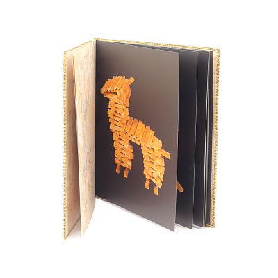 Open beige art book showing an animal figure constructed from small wooden planks on a black page.