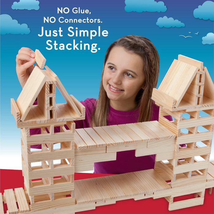 Girl stacking light wood planks into a bridge and towers structure against a blue sky background.