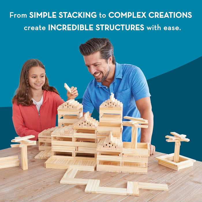 Man and child building complex architectural structures with small, light wood rectangular planks on a table.