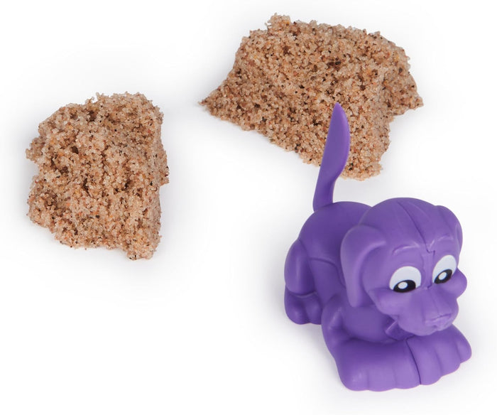 Purple toy dog figurine and two mounds of textured natural brown kinetic sand on a white background.