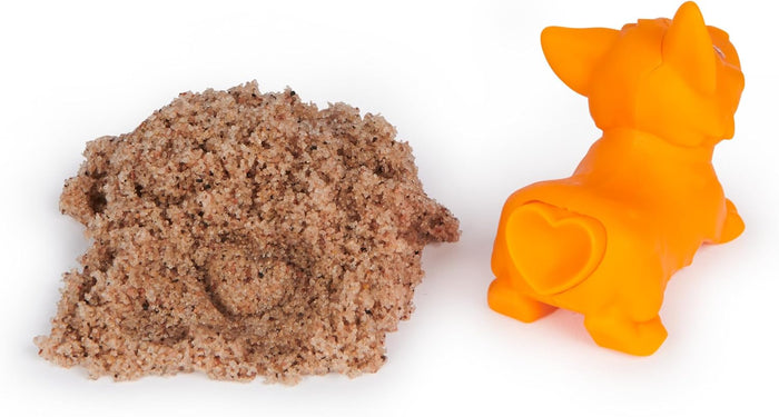 Speckled brown kinetic sand next to an orange plastic dog toy with a heart-shaped indentation.