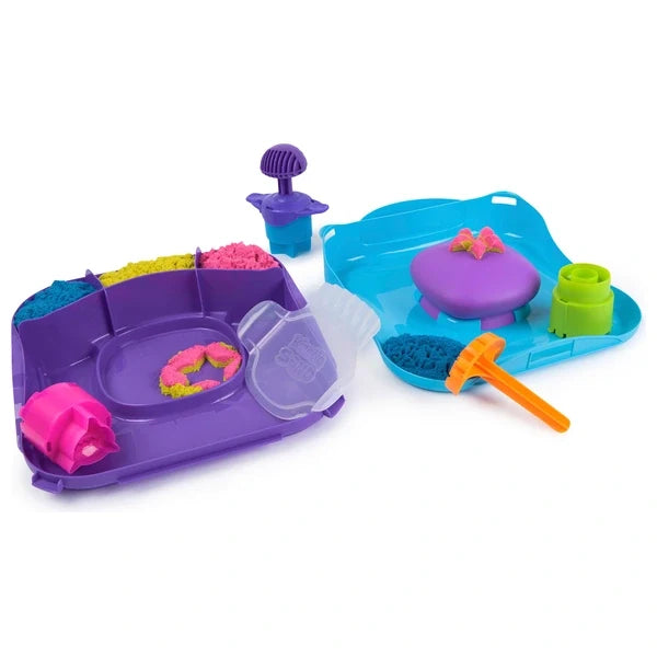 Kinetic sand play set with purple and blue trays, colorful sand, and tools for squishing and shaping sand designs.