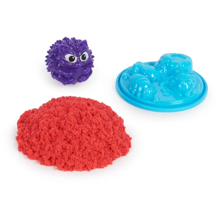 Purple hedgehog critter, blue animal-shaped sand mold, and a pile of bright red kinetic sand.