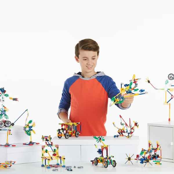 Smiling boy builds colorful K'NEX models like cars and robots using vibrant plastic rods and connectors.
